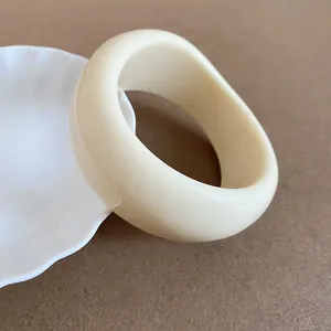 Close-up of a chunky cream resin bangle with a smooth, irregular geometric design