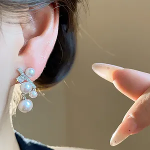 Primo piano di eleganti orecchini a perno con perle in stile francese e zirconi sull'orecchio