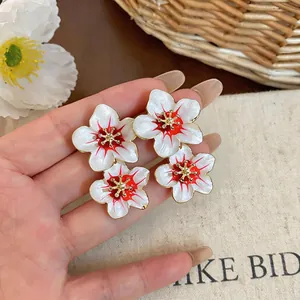 Detailed view of elegant white and red floral drip oil stud earrings with gold accents