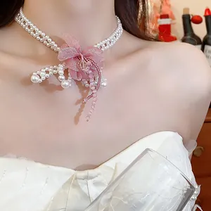 Close-up detail of a sweet pink chiffon flower and elegant double-strand pearl necklace