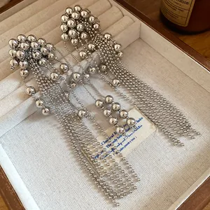 Detailed view of silver metallic beaded long tassel earrings displayed in a luxury jewelry box