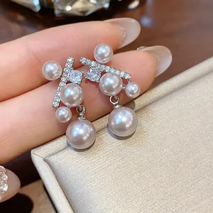 Dettaglio ravvicinato di eleganti orecchini in argento con perle e pietre di zirconi.