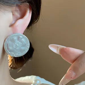 Close-up of vintage matte silver stud earring with embossed floral pattern detail