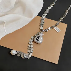Close-up of silver long sweater chain with sparkling diamond money bag and pearl.