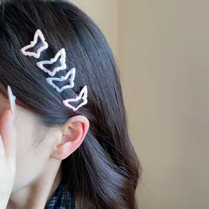 Detail macro view of four colorful hollow butterfly hair clips worn by a model in soft light