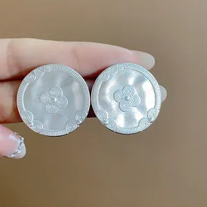 Detailed view of vintage matte silver stud earrings with intricate floral engravings
