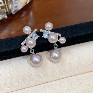 Primo piano di eleganti orecchini in argento con zirconi e perle pendenti raffinate.