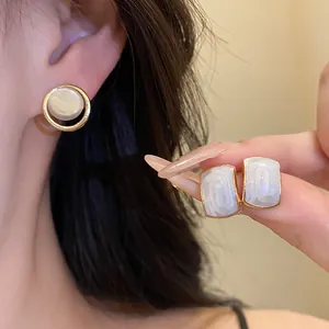 Gros plan montrant la texture exquise de boucles d'oreilles en résine dorée sur un modèle