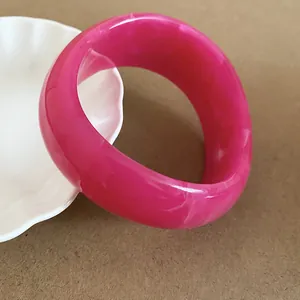 Close-up of a thick magenta resin bangle with elegant white marbled patterns