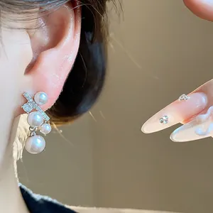 Primo piano di un elegante orecchino a pendente con perla e zircone indossato sull'orecchio