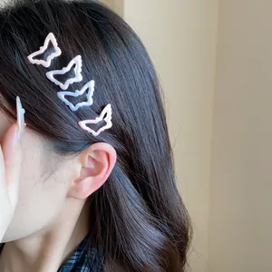 Close-up of four cute butterfly-shaped hair clips in pink and blue on dark hair