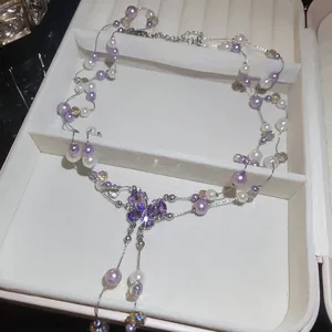 Detailed view of elegant purple pearl necklace with butterfly crystal pendant in box