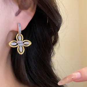 Gros plan d'une élégante boucle d'oreille fleur plaquée or 18 carats avec zircons sur l'oreille