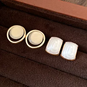 Détail de boucles d'oreilles géométriques en résine dans un luxueux coffret à bijoux marron
