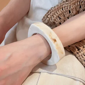 Detail view of an irregular geometric resin bangle with marble texture on a model wrist.
