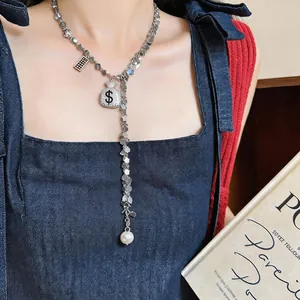 Detail of long tassel necklace featuring rhinestone money bag pendant and pearl drop