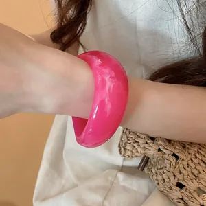 Close-up of a pink marbled resin bangle with an irregular geometric design on a wrist