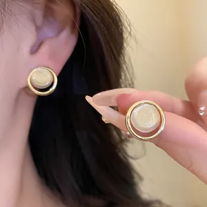 Gros plan de boucles d'oreilles rondes en résine avec cadre doré et fini perlé élégant