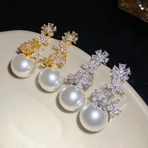 Detailed view of elegant zircon flower and pearl drop earrings in gold and silver