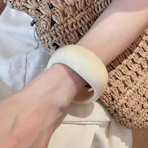 Close-up of a minimalist cream-colored resin geometric irregular chunky bangle on wrist.