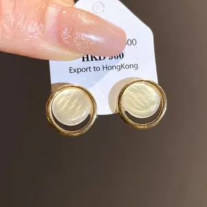 Gros plan de boucles d'oreilles rondes en résine avec cadres dorés et effet oeil de chat