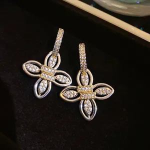 Gros plan sur des boucles d'oreilles fleuries dorées serties de zircons étincelants.
