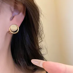 Gros plan d'une puce d'oreille ronde en résine avec finition dorée
