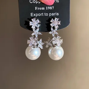 Close-up of elegant flower zirconia and pearl drop earrings on display