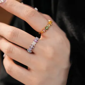 Detailed close-up of elegant gold and silver rings with colorful zircon flowers on hand