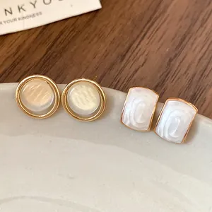 Détail de boucles d'oreilles élégantes en résine à cadre doré avec finitions nacrées