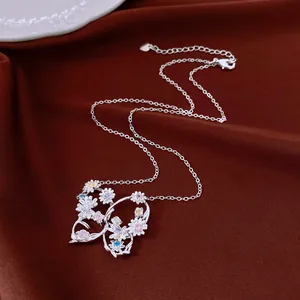 Détail du collier papillon en argent avec fleurs en zircon coloré sur tissu marron