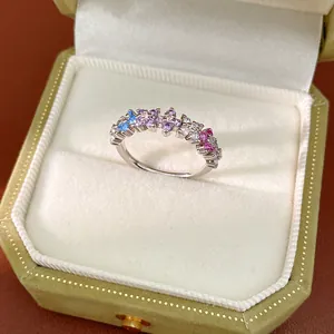 Close-up detail of an elegant silver ring featuring multi-color zircon stones in velvet box