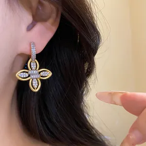 Gros plan d'une boucle d'oreille fleur en or 18 carats avec zircones sur l'oreille.