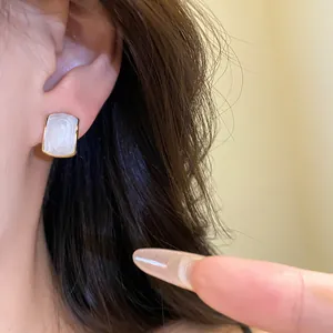 Gros plan d'une boucle d'oreille rectangulaire minimaliste en résine avec cadre doré