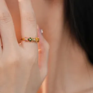 Detailed view of an exquisite gold ring set with colorful zircon stones on a model's finger