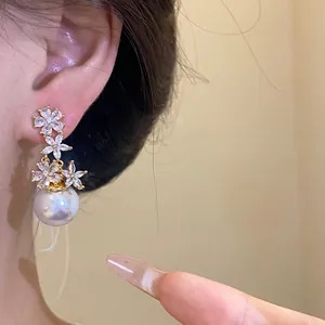 Detailed view of elegant silver needle zircon flower earrings with a large pearl on ear