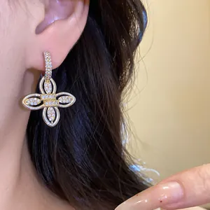 Gros plan de boucles d'oreilles fleurs plaquées or 18k avec zircons brillants sur l'oreille