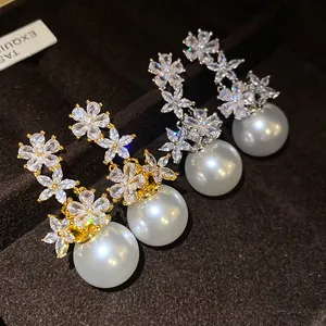 Detailed view of elegant silver needle zircon flower earrings with large white pearls
