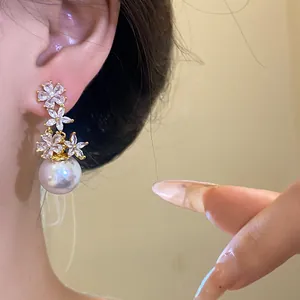 Detail shot of elegant silver needle zircon flower earrings with large pearl drops