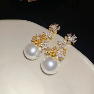 Close-up of elegant zircon flower earrings with large lustrous white pearls on a dish