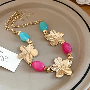 Close-up macro view of vintage gold flower necklace with pink and teal accent beads