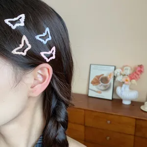 Close-up of a model wearing four colorful butterfly enamel hair clips in dark hair.