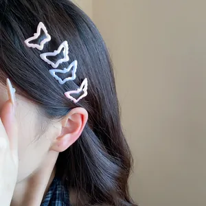 Detail of four colorful enamel butterfly hair clips worn on side of wavy dark hair.