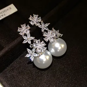 Close-up of elegant flower pearl earrings with sparkling zirconia and silver needle