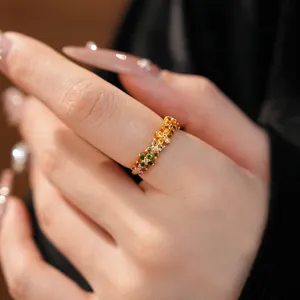 Close-up detail of a gold flower ring with colorful zircon stones worn on a finger