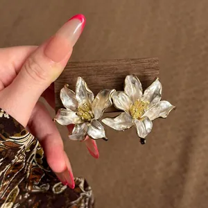 Primer plano detallado de pendientes de lirio blanco perlado con bordes dorados