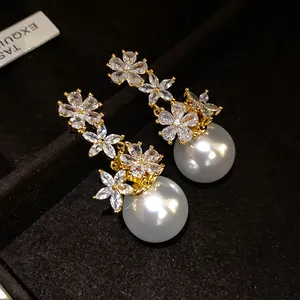Close-up of elegant zircon flower and pearl drop earrings displayed on black velvet.