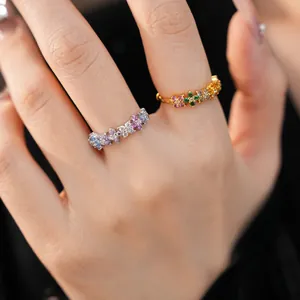 Detailed close-up view of two delicate colorful zircon flower rings on model's finger