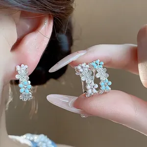 Orecchini a forma di C con fiori in smalto e zirconi brillanti su aghi in argento.