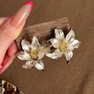 Detalle de elegantes pendientes de flores blancas sobre soporte madera